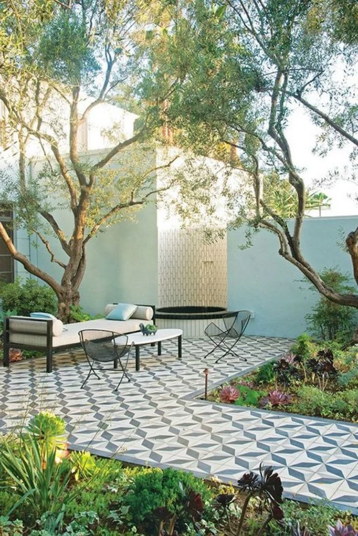 tiled pathway and floor, lounge chair, black metal chairs, covered porch ideas, tall trees, greenery and bushes