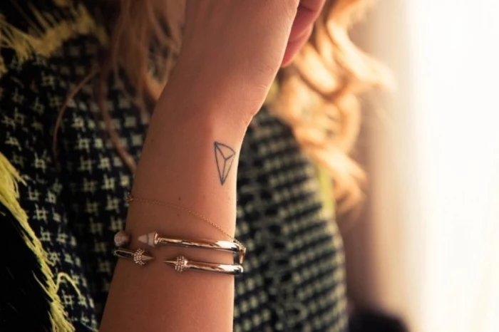 small tattoo placement, geometrical triangle, wrist tattoo, silver bracelets, blonde curly hair