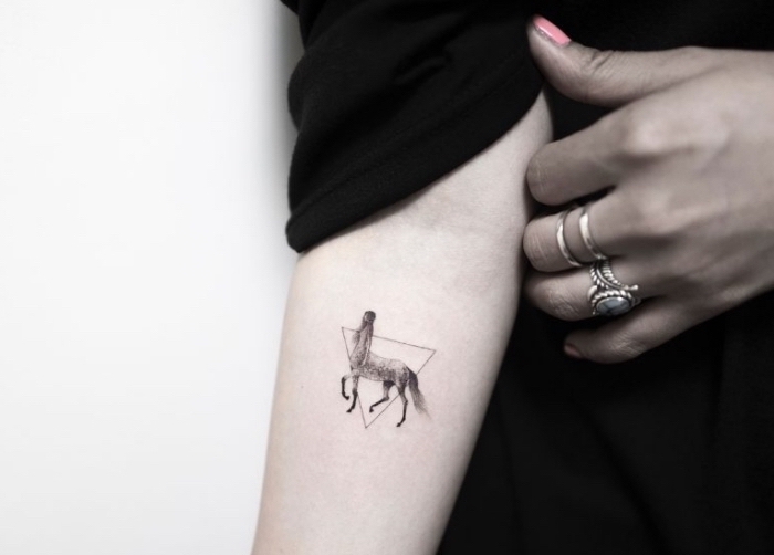 small hip tattoos, female centaur, inside a triangle, forearm tattoo, black blouse, pink nail polish