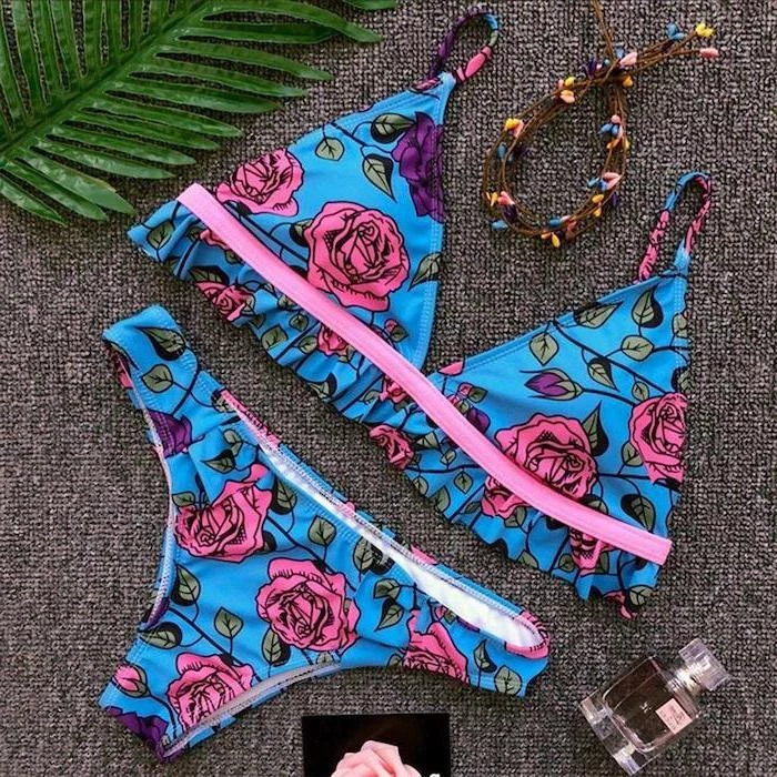 cute swimsuits for girls, blue with pink roses print, grey background, perfume bottle, palm leaf