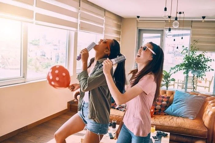 two girls, singing karaoke, with hairbrushes, party theme ideas, beige leather sofa, red balloon