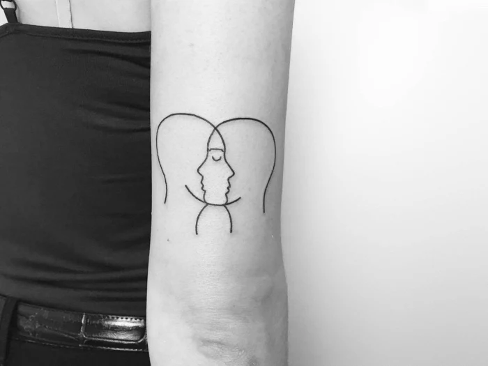 two silhouettes intertwined, back of arm tattoo, small hip tattoos, black and white photo