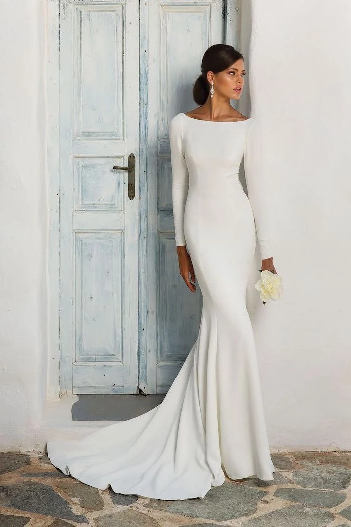 white flower bouquet, chiffon wedding dress, long white dress, wooden door, black hair, in a low updo
