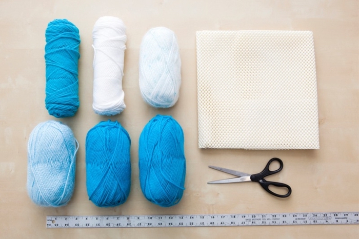 white yarn, shades of blue yarn, white plastic mat, black scissors, long ruler, easy diys