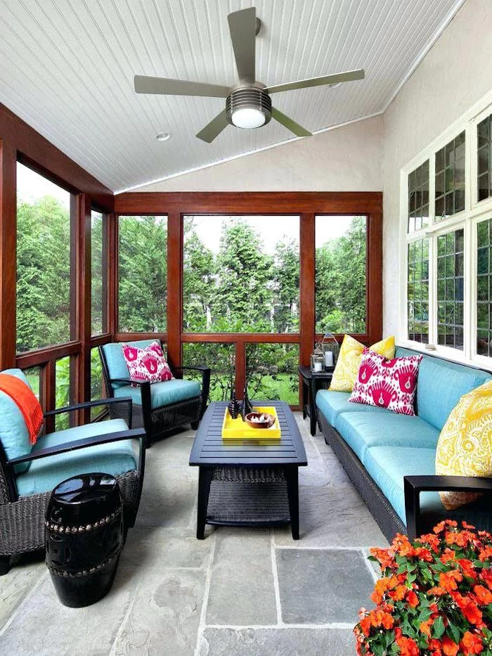 ceiling fan, black wooden furniture, blue cushions, yellow and pink, printed throw pillows, front porch railing ideas