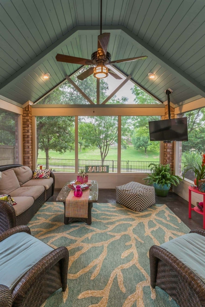 a shaped ceiling, blue and beige rug, wooden sofa and armchairs, blue and grey cushions, front porch decor