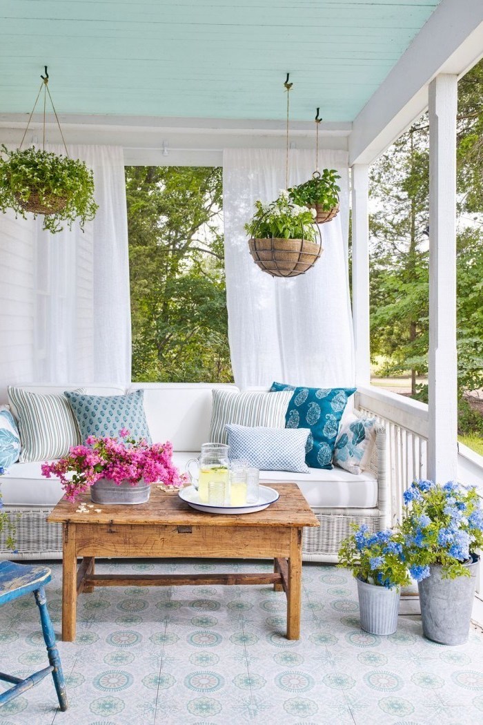 front porch decor, hanging plants, white curtains, blue and grey throw pillows, vintage wooden table
