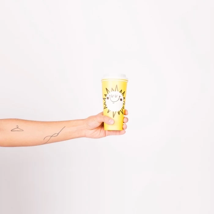 yellow paper, coffee cup, hanger and needle, forearm tattoos, subtle tattoos, white background