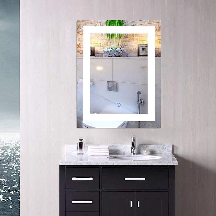 white wall, mirror with lights, black makeup vanity, marble countertop, with sink