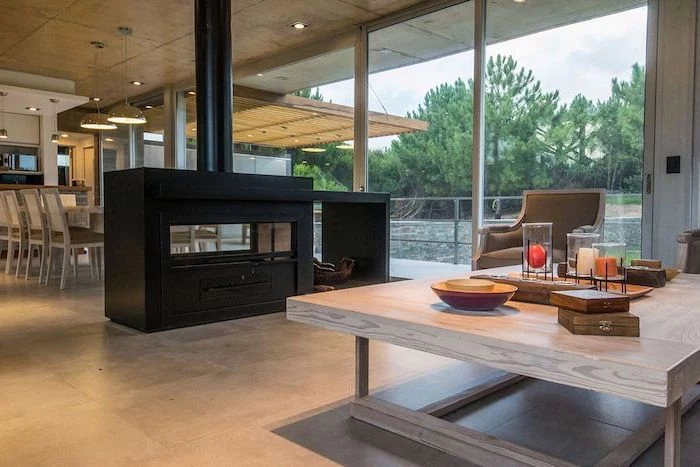 black fireplace, screen dividers, tall windows, wooden table, grey leather armchair, tiled floor
