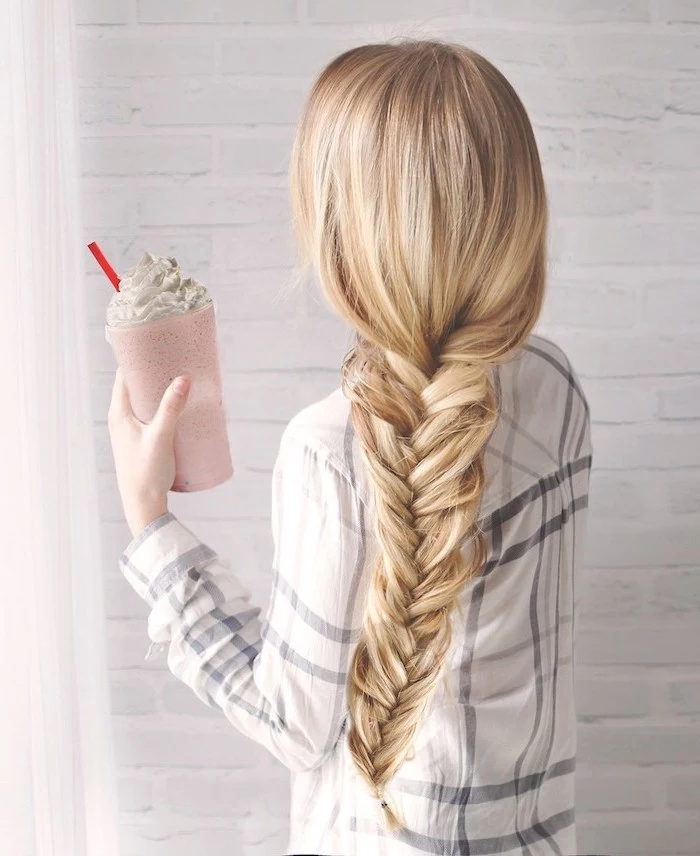 blonde hair, in a fishtail braid, plaid shirt, holding a milkshake, braid hairstyles, white brick wall