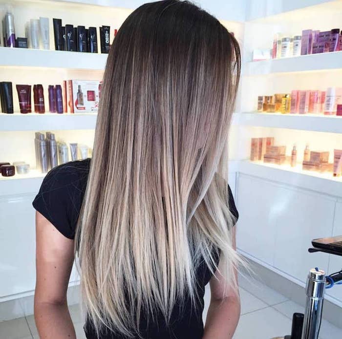 brown to blonde, long and straight, silver ombre hair, black shirt, shelves with hair products
