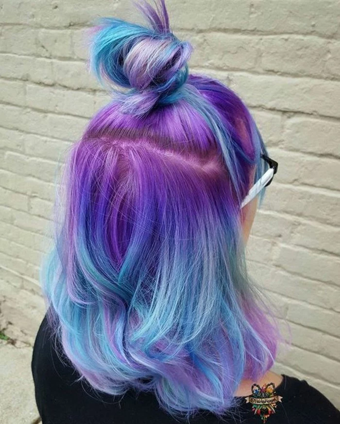 unicorn hair, silver ombre hair, purple to blue in a bun, white brick wall, black shirt