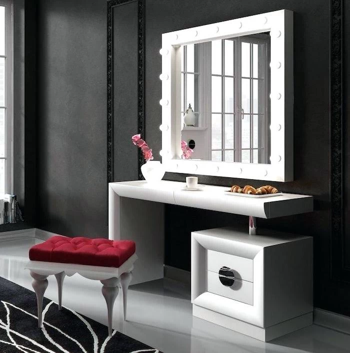 black makeup vanity, black wall, white shelf and drawer, mirror with lights, red velvet stool