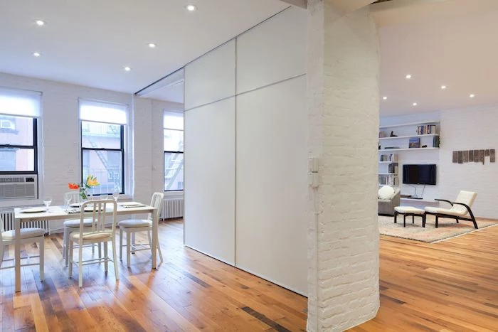 white brick wall, wooden floor, wooden room dividers, white panels, white chairs, dining table