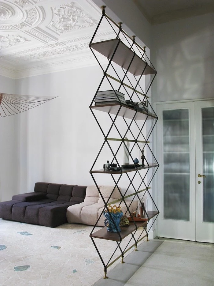 metal triangles and bookshelves, hanging room dividers, white carpet, black and white sofa
