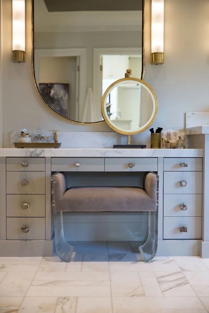 mirrored vanity table, grey drawers, marble countertop, grey velvet ottoman, tiled marble floor