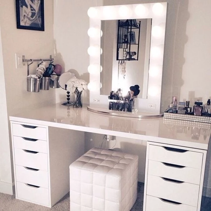 mirror with lights, white leather ottoman, makeup vanity chair, white drawers, tray full of perfumes