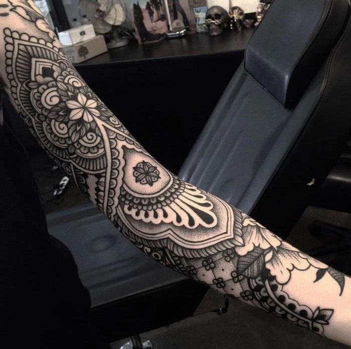 mandala tattoo, black leather armchair, black top, skull sleeve tattoo