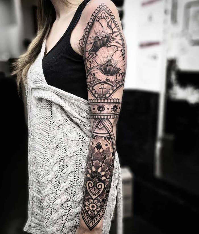 floral mandala, grey cardigan, black top, forearm sleeve tattoo, blurred background