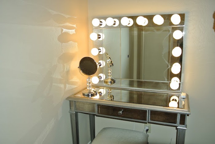 mirror with lights, makeup vanity chair, mirrored countertop, table with a drawer, white walls