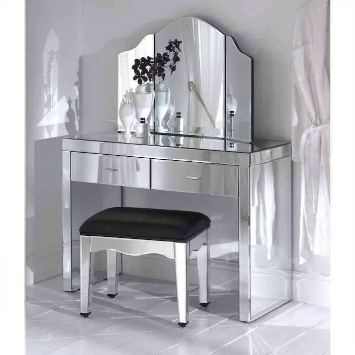 mirrored table, black leather stool, three fold mirror, white makeup vanity, white wall, tiled floor