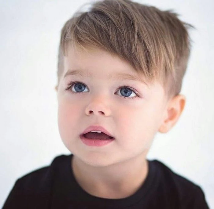 toddler boy, with blue eyes, blonde hair, long hairstyles for boys, black shirt, white background