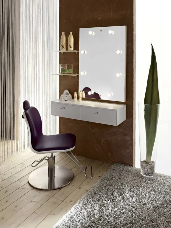 mirror with lights, purple leather chair, wooden floor, grey carpet, small makeup vanity, white floating shelf