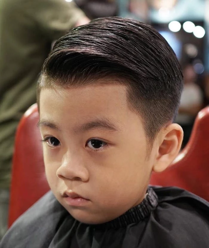 little boy, in a red chair, side swept, black hair, types of haircuts for men, black eyes