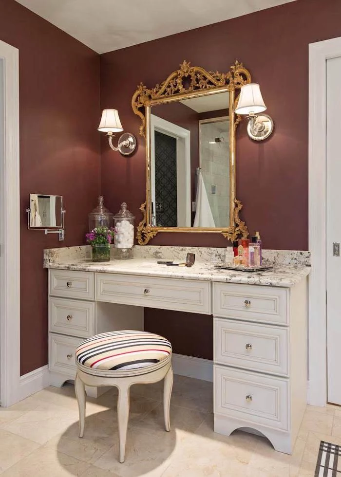 dark red walls, vintage mirror, white table, with drawers, marble countertop, corner makeup vanity