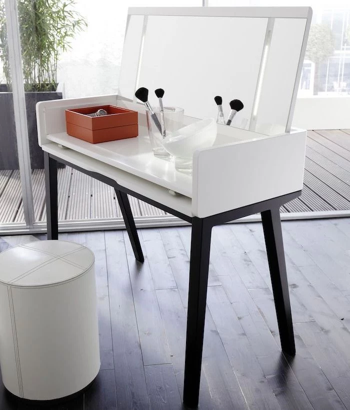 wooden floor, white leather ottoman, makeup vanity table with lighted mirror, pull out mirror