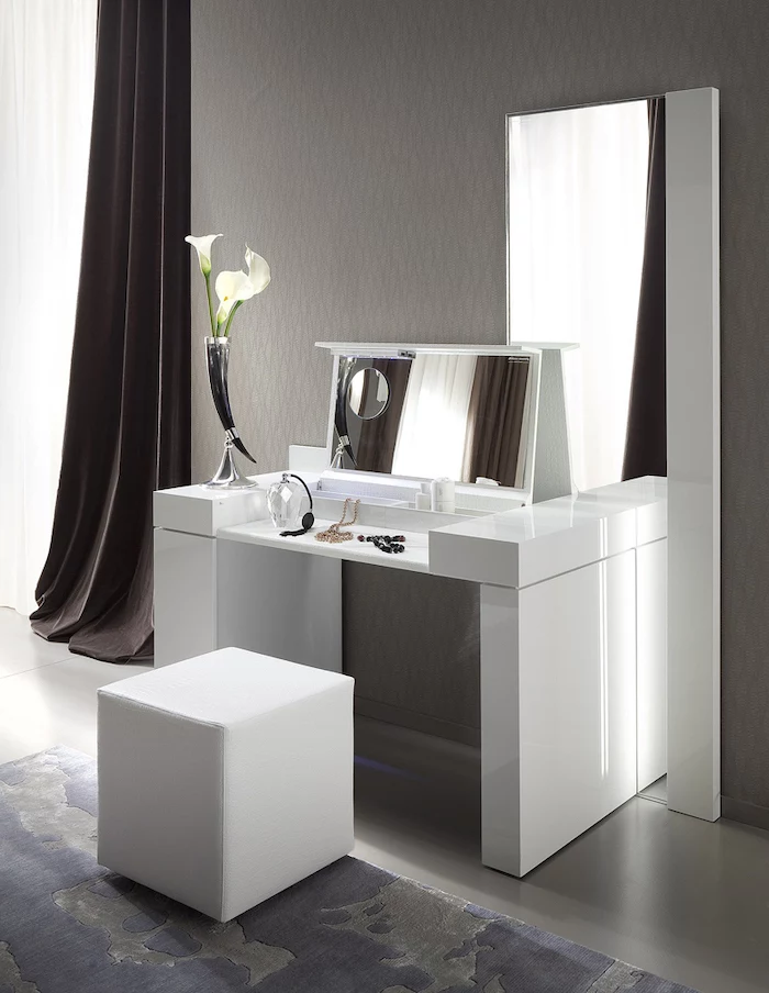 makeup vanity, white table, pull out mirror, white leather ottoman, grey and blue carpet, grey walls