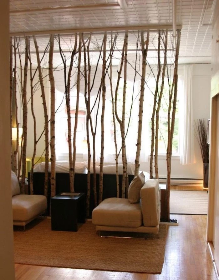 indoor privacy screen, made of tree branches, white armchairs, wooden floor, beige carpet