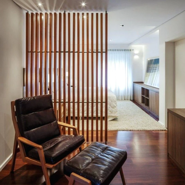 wooden poles, portable room dividers, black leather armchair, wooden floor, white carpet