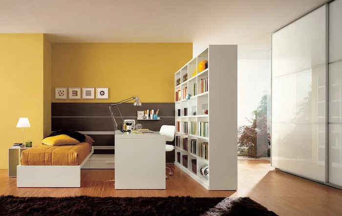 yellow wall, glass panels, white bookcase, decorative room dividers, wooden floor, black carpet