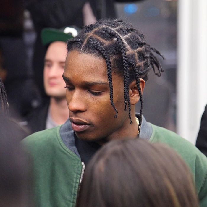 asap rocky, with black hair, wearing a green blazer, braids for men, surrounded by people