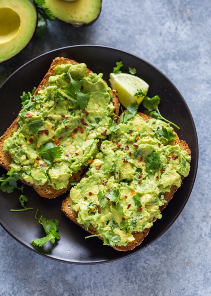 avocado toast, on black plate, herbs on top, brunch recipes, lemon slice, granite countertop