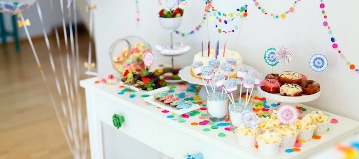 colorful decorations, on a white wooden table, cake and donuts, cake pops, popcorn in a cup, baby shower ideas for girls