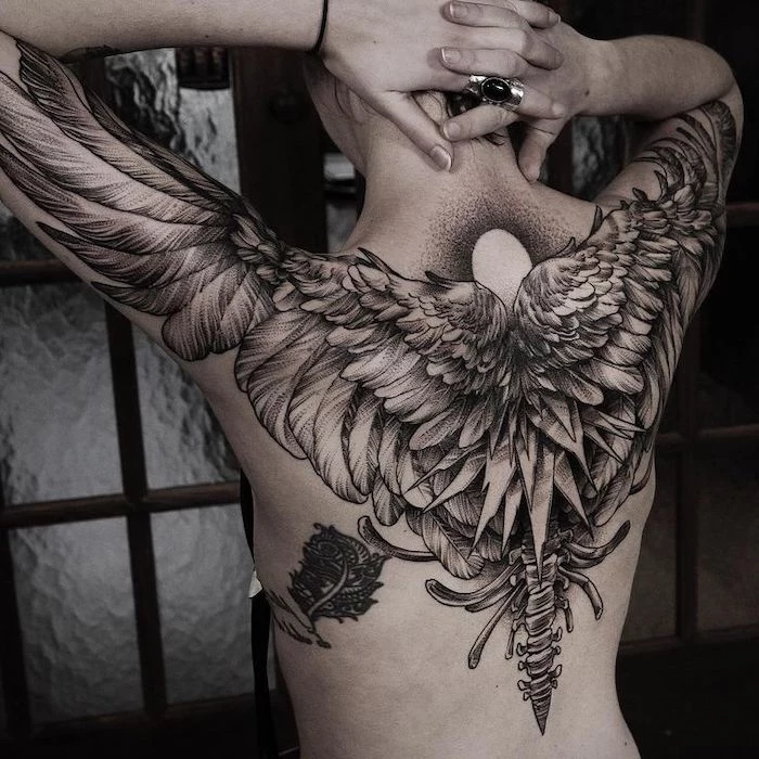 wings tattoo on back, large tattoo, extending to the shoulders and arms, large silver ring