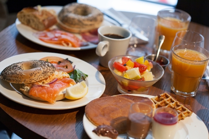 halved bagels, salmon and tomatoes inside, brunch menu, orange juice and coffee, fruit bowl