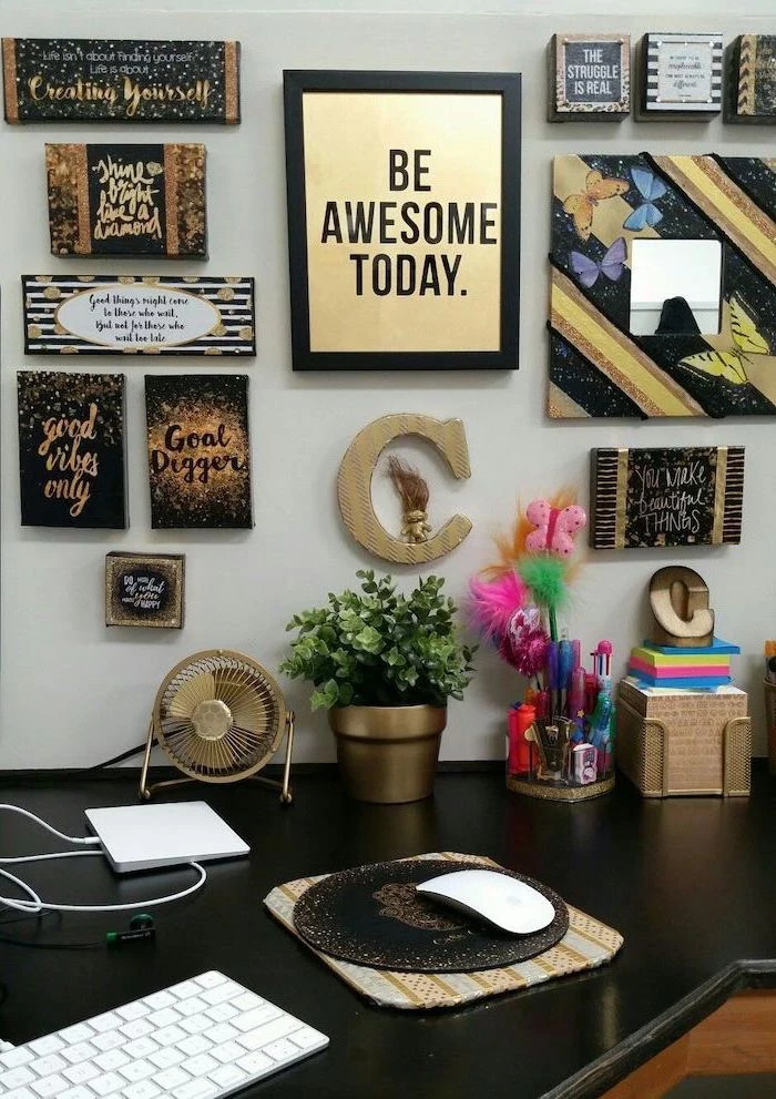 cubicle decor, framed art, hanging on the wall, black desk underneath, gold desk accessories