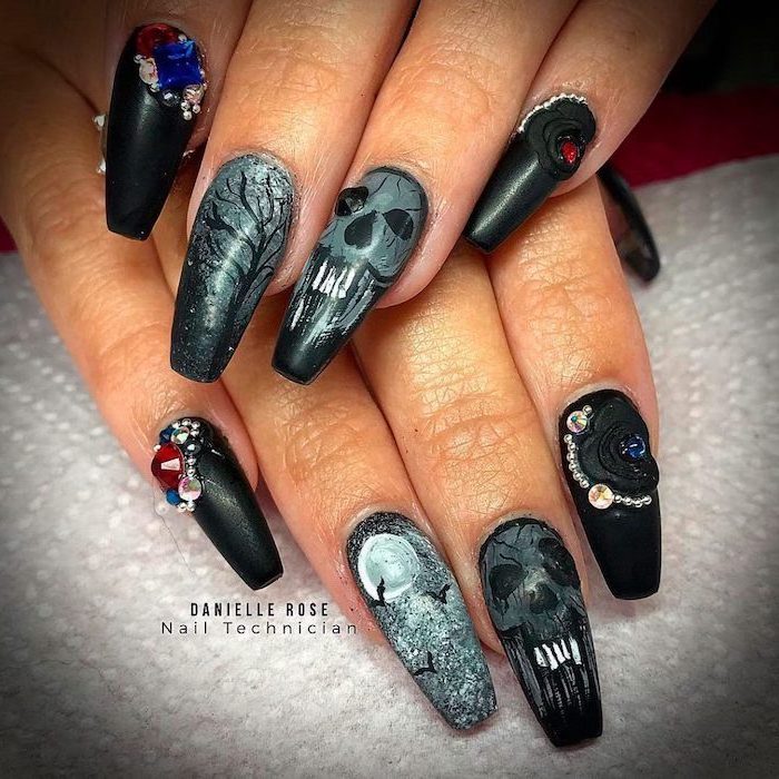 black and grey matte nail polish, halloween nails, skulls and spooky forrest decorations, red and blue rhinestones