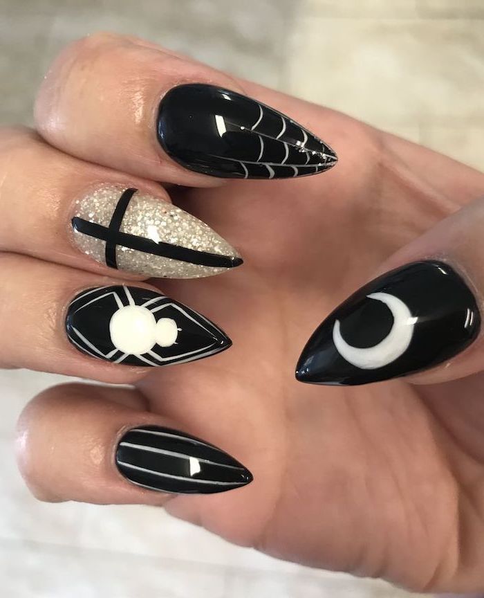 black nail polish, gold glitter, halloween acrylic nails, white spider web decorations, long stiletto nails