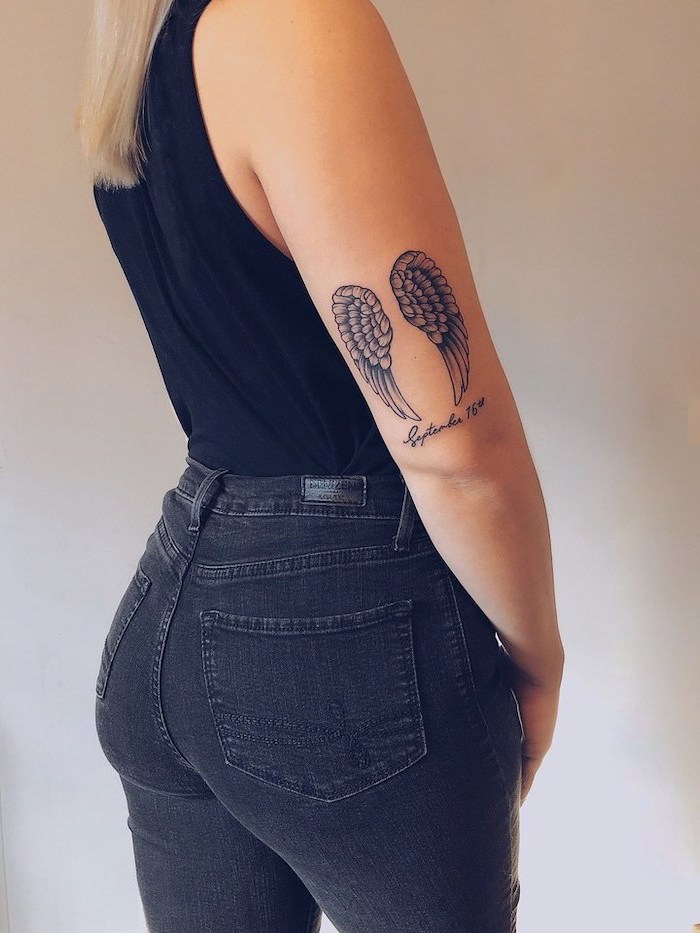 back of arm tattoo, above the elbow, fallen angel tattoo, woman with jeans, black top, blonde hair