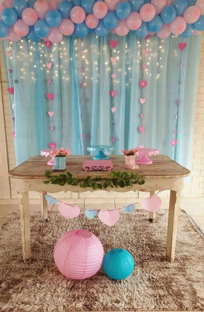 blue and pink balloons, blue tulle, fairy lights, gender reveal themes, wooden table, cake stands