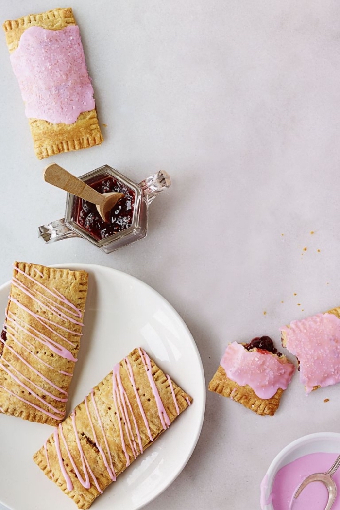 baked pastries, with blueberry jam, pink frosting, good breakfast ideas, white plate
