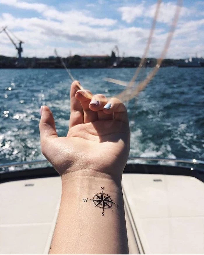 sea wives, ship pier, compass tattoo meaning, wrist tattoo, white boat, cloudy sky, in the background