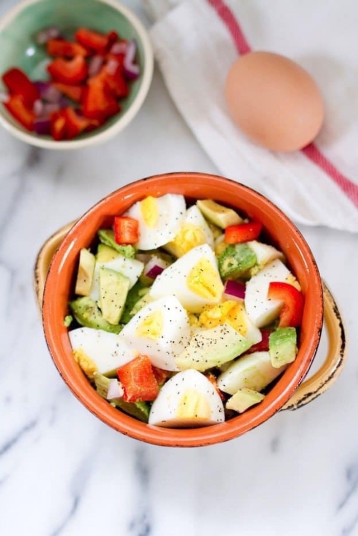 breakfast food ideas, boiled eggs, with chopped peppers and avocado, in a ceramic bowl