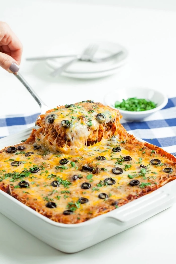 baked casserole, with olives and chives on top, breakfast food ideas, metal spatula, white table