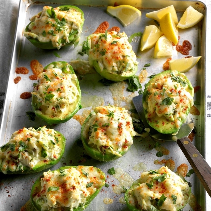 halved avocados, baked with vegetables, cheese on top, lemon slices, breakfast food ideas